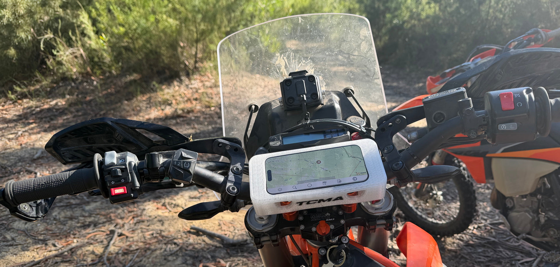 Close-up of a motorcycle handlebar with a digital display in a natural setting